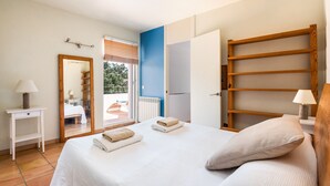 Ein Schlafzimmer mit Bett, Nachttisch, Spiegel, Kleiderschrank und Blick ins Freie.