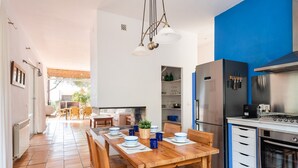 Eine moderne Küche mit Essbereich, mit einem Holztisch für vier Personen, einem eingebauten Backofen und einer blauen Akzentwand.