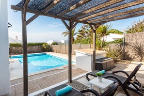 A covered outdoor area with a pool, seating, and a small table with a plant.