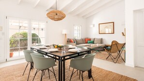 A spacious dining area with a wooden table, four chairs, and a hanging light fixture.