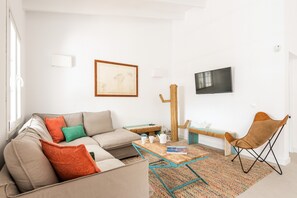A living room with a sofa, coffee table, and a TV mounted on the wall.