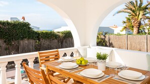 A dining area with a wooden table set for two, white plates, and a bowl of green apples.
