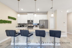 A modern kitchen with white cabinets, stainless steel appliances, and a central island with bar stools.