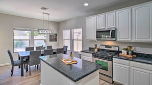A modern kitchen with white cabinets, a granite countertop, and a central island. - Game Room, Putting Green! Queen Creek Family Home (Queen Creek)