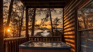 Une cabane en bois dotée d’un bain à remous, d’une terrasse en bois et offrant une vue sur les arbres et les montagnes.