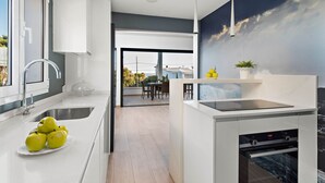 A modern kitchen with a built-in oven, a sink, and a dining area with a view. - Villa Caterina - Playa de Punta Prima (San Luis)