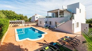 A modern villa with a swimming pool, outdoor seating, and a staircase leading to an upper level. - Villa Caterina - Playa de Punta Prima (San Luis)
