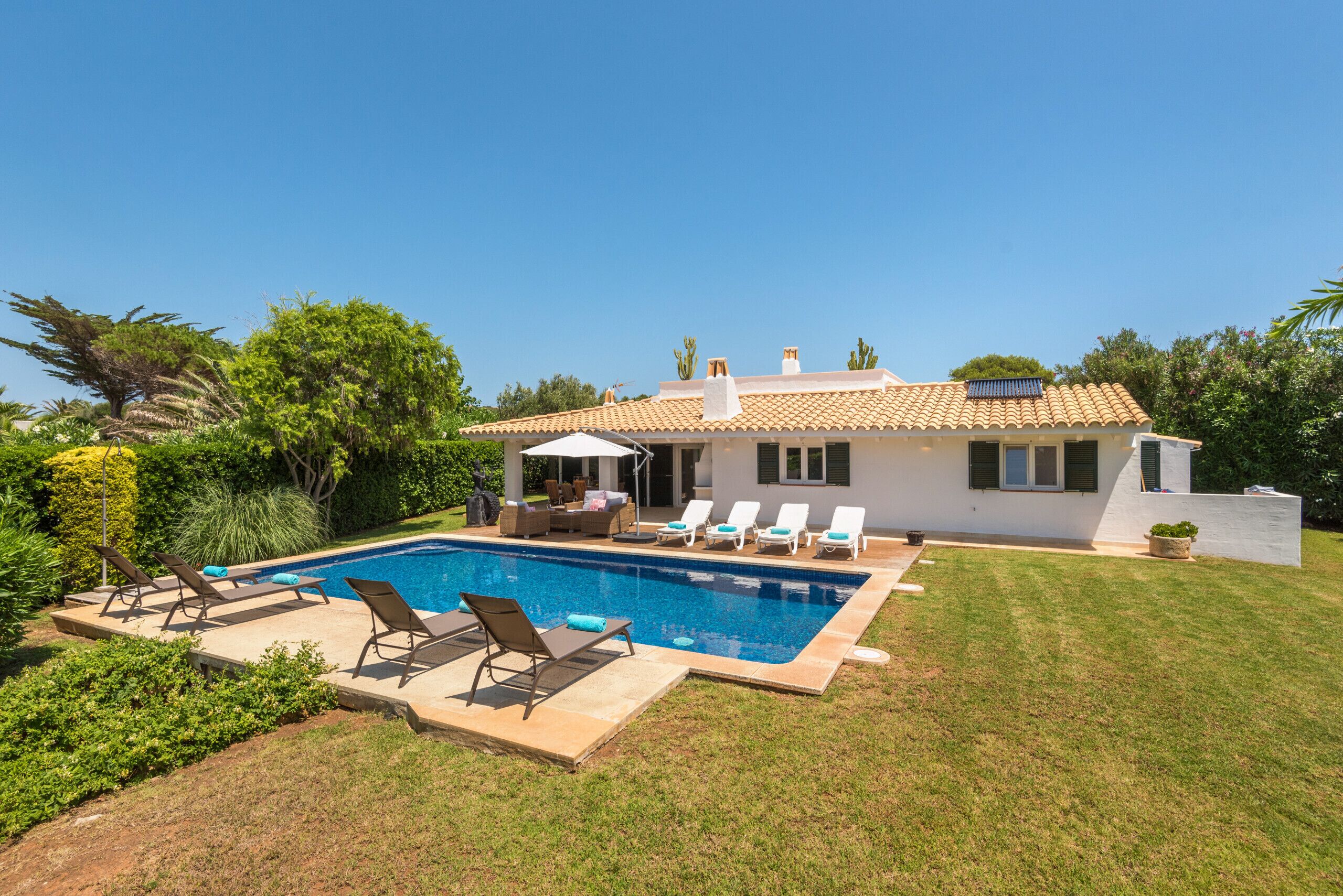 A modern house with a swimming pool, outdoor furniture, and a well-maintained lawn.