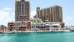 Un hotel frente al agua con varios edificios altos, una bandera y un muelle con barcos.