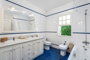 Un baño con dos lavamanos, un inodoro, un bidé y una bañera.