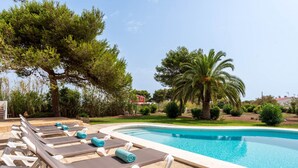 A swimming pool with lounge chairs and towels, surrounded by trees and a clear sky. - Hort des Milord - Villa en Es Castell (Es Castell)