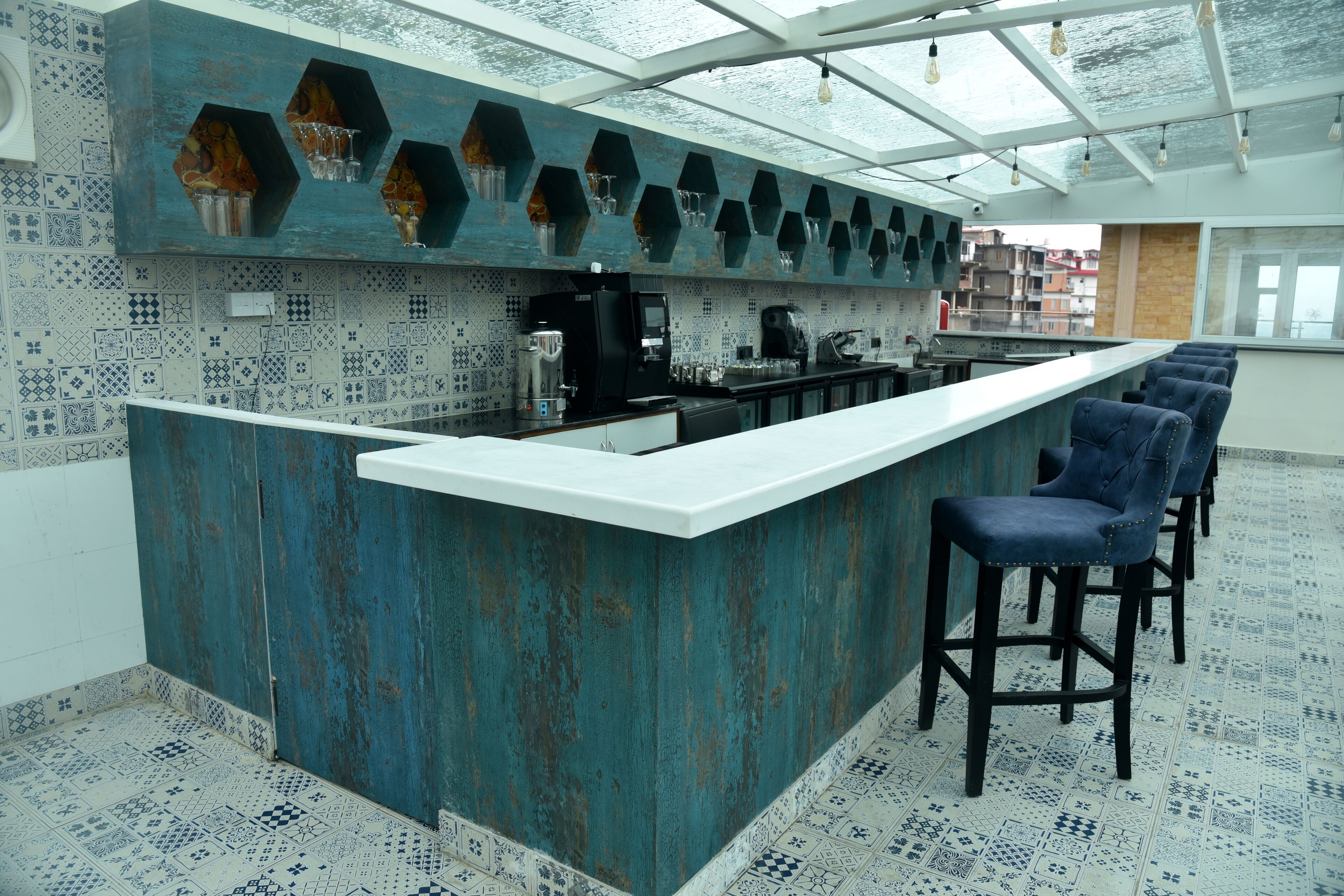A modern kitchen with a bar area, hexagonal shelves, and patterned tiles.