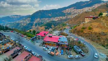 A hilly town with a winding road, buildings with red roofs, and a view of the surrounding mountains.