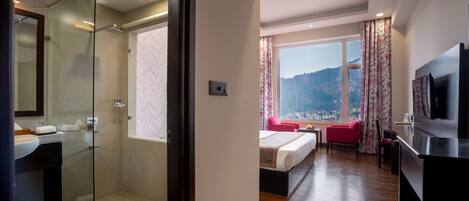 A modern hotel room with a glass shower, a large bed, a TV, and a view of a cityscape through a large window.