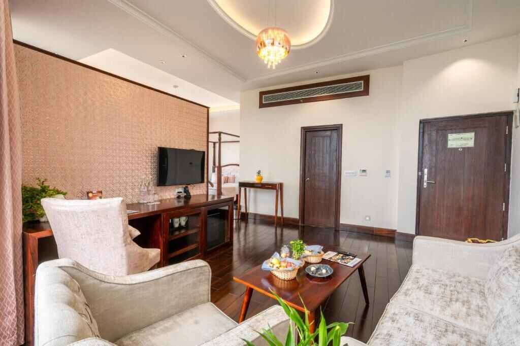 A modern living room with a flat-screen TV, a dining table with chairs, and a sofa.