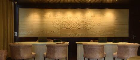 Un área de recepción con un gran mural de madera, una mesa de recepción y cuatro sillones cómodos.
