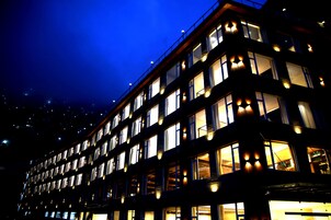 Un edificio de varios pisos con ventanas y balcones iluminados en la noche.