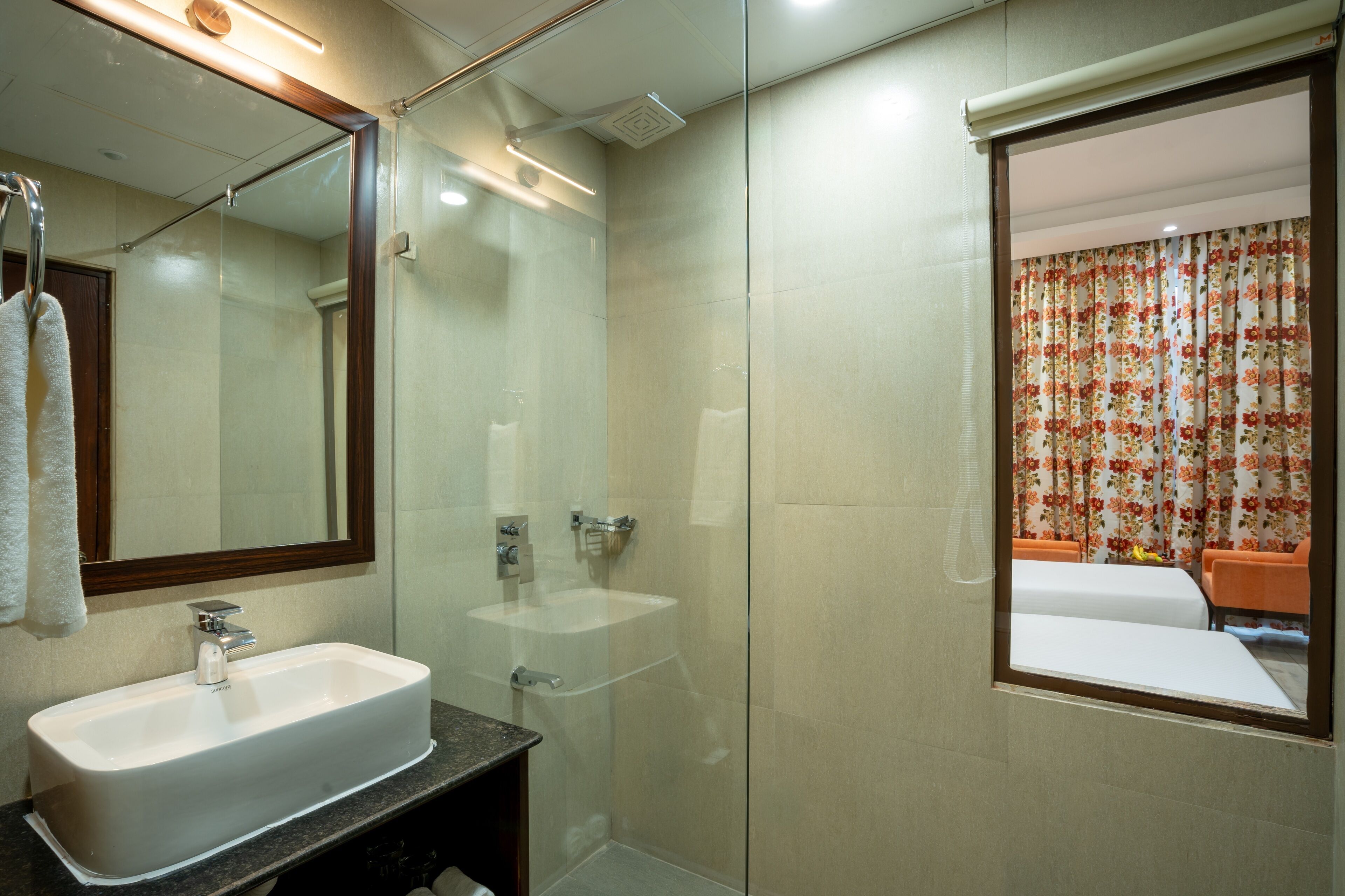 Een badkamer met een grote spiegel, een wastafel en een douche.