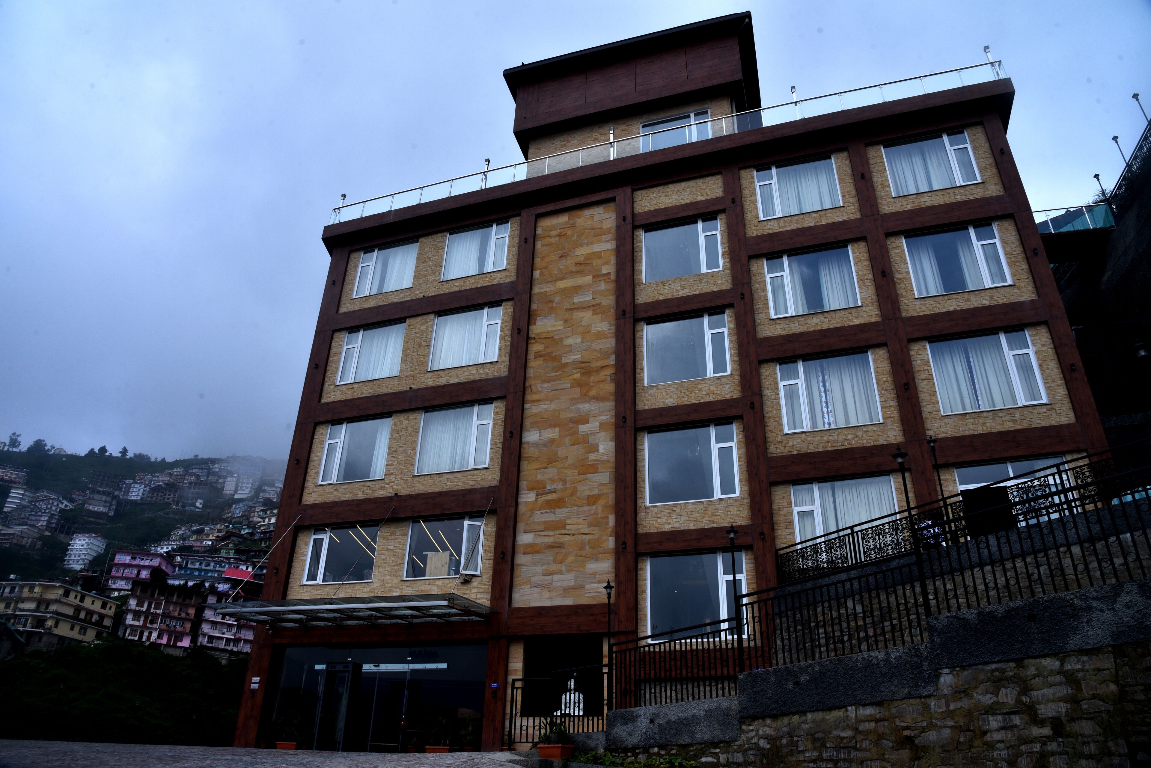 Ein mehrstöckiges Hotel mit einer zentralen Steinfront, zahlreichen Fenstern und einem Balkon im oberen Stockwerk.