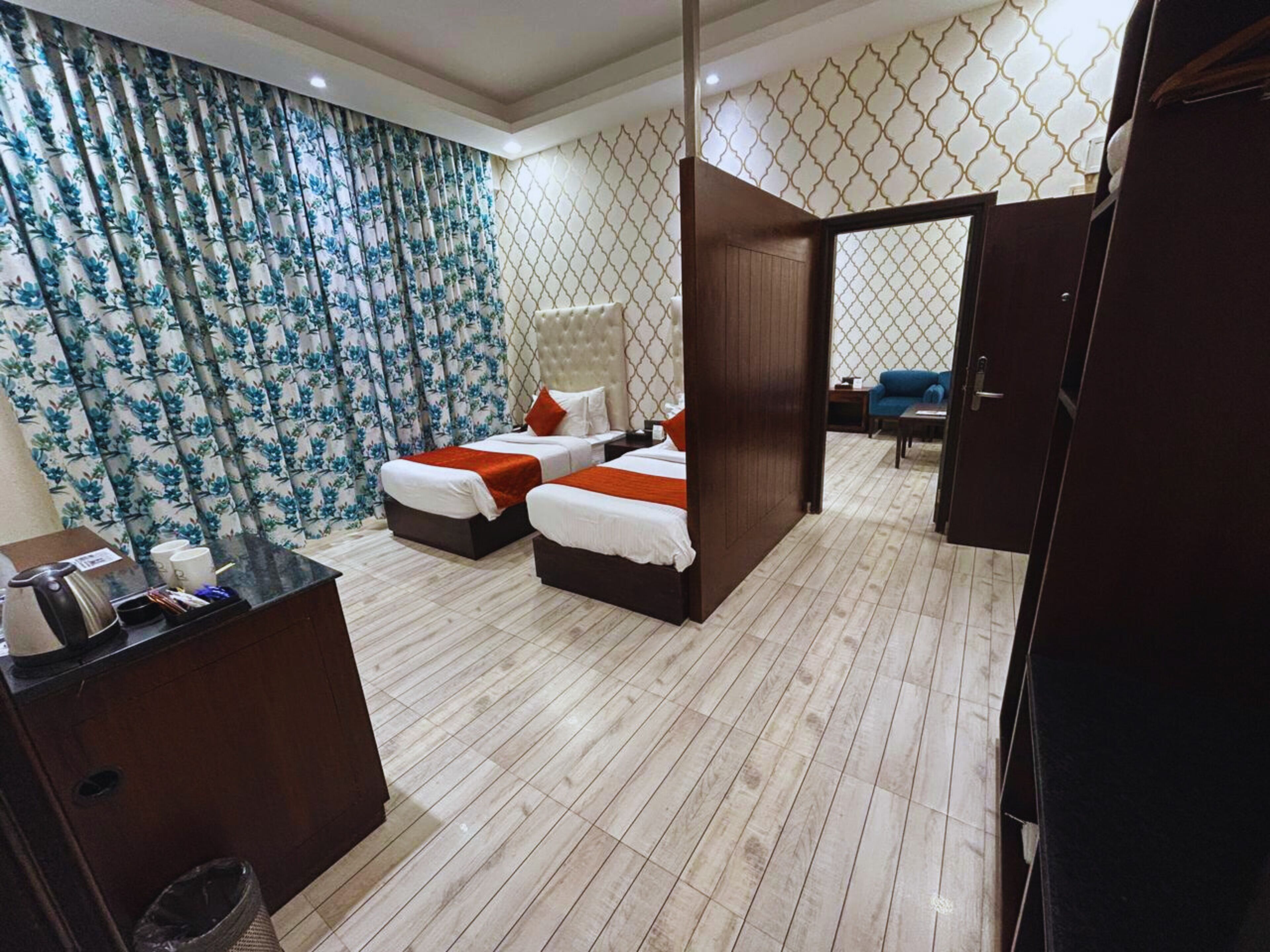 A hotel room with two beds, a desk, a chair, and a small table.