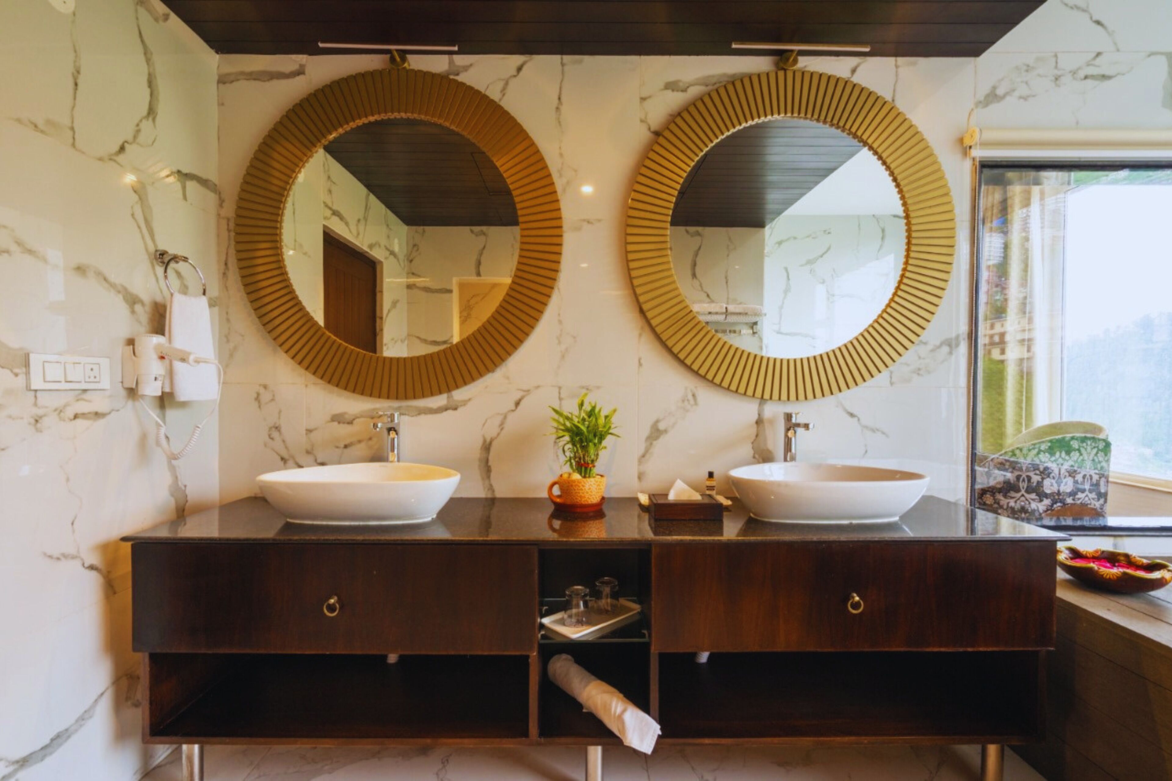 A bathroom with two sinks, marble walls, and two large mirrors.