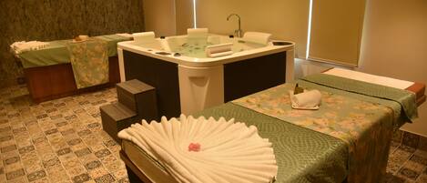 Un cuarto de spa con dos camillas de masaje, una bañera grande y un lavamanos pequeño.
