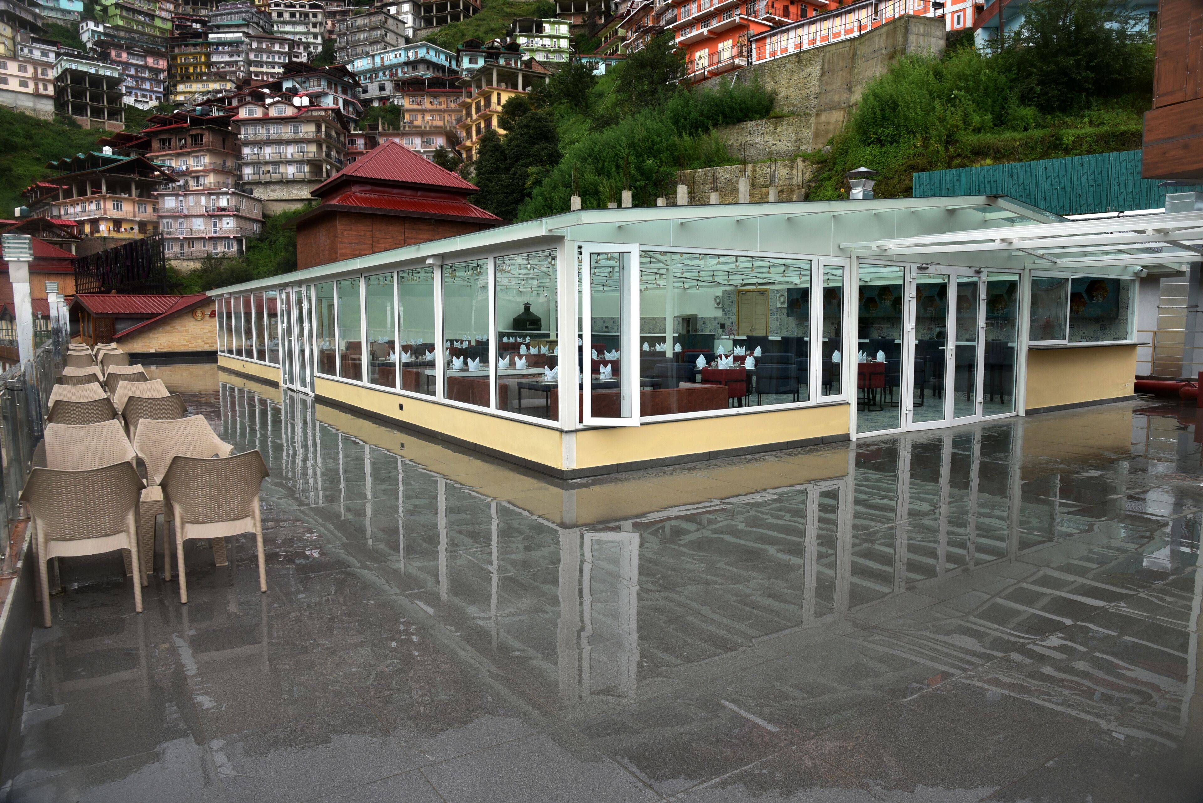 A covered outdoor seating area with tables and chairs, surrounded by a glass enclosure.