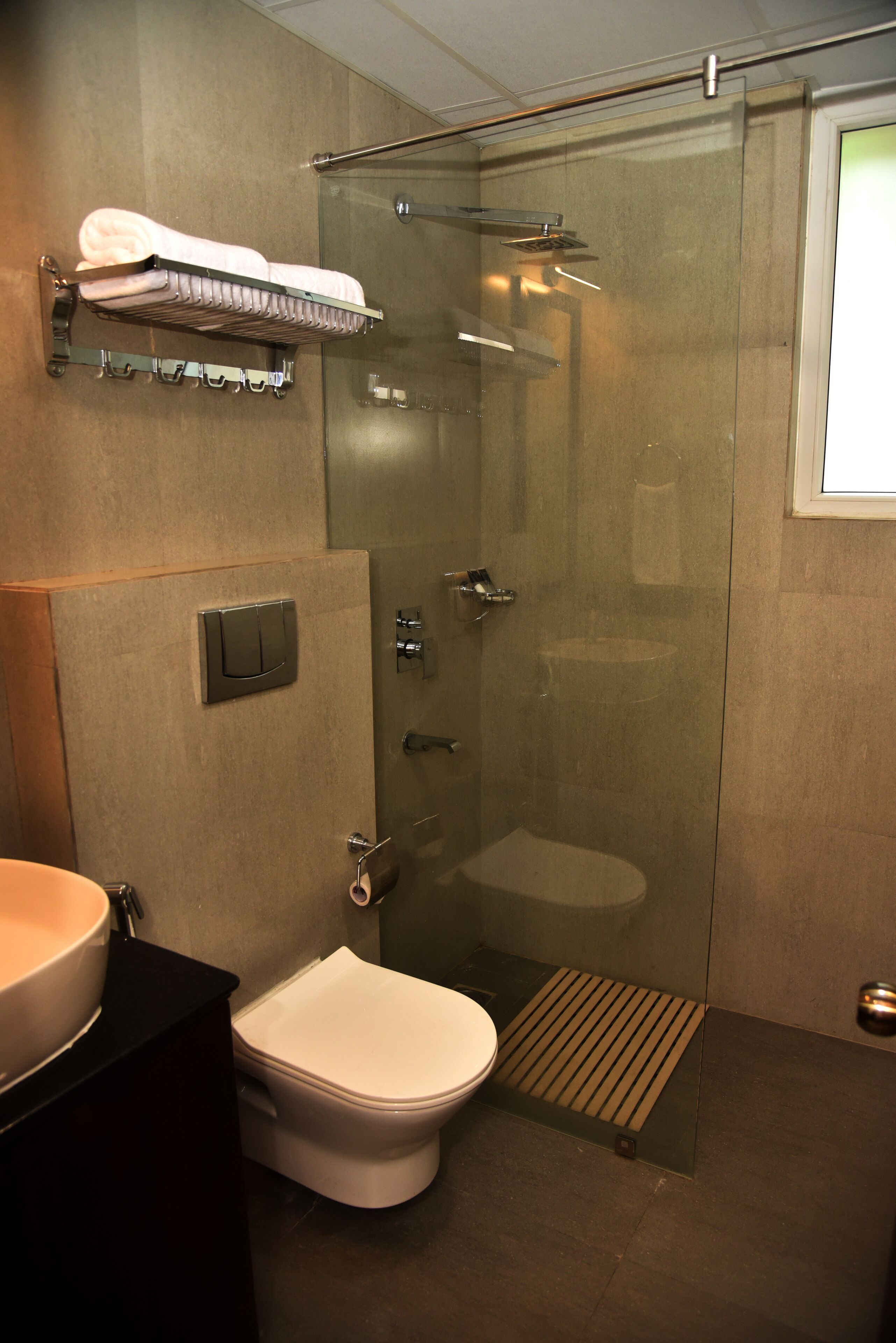 A modern bathroom with a glass-enclosed shower, a toilet, and a sink.