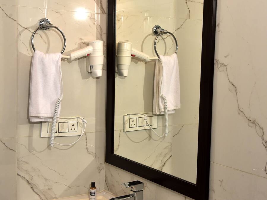 Ein Badezimmer mit einem weißen Waschbecken, einem Spiegel und zwei an der Wand montierten Haartrocknern.