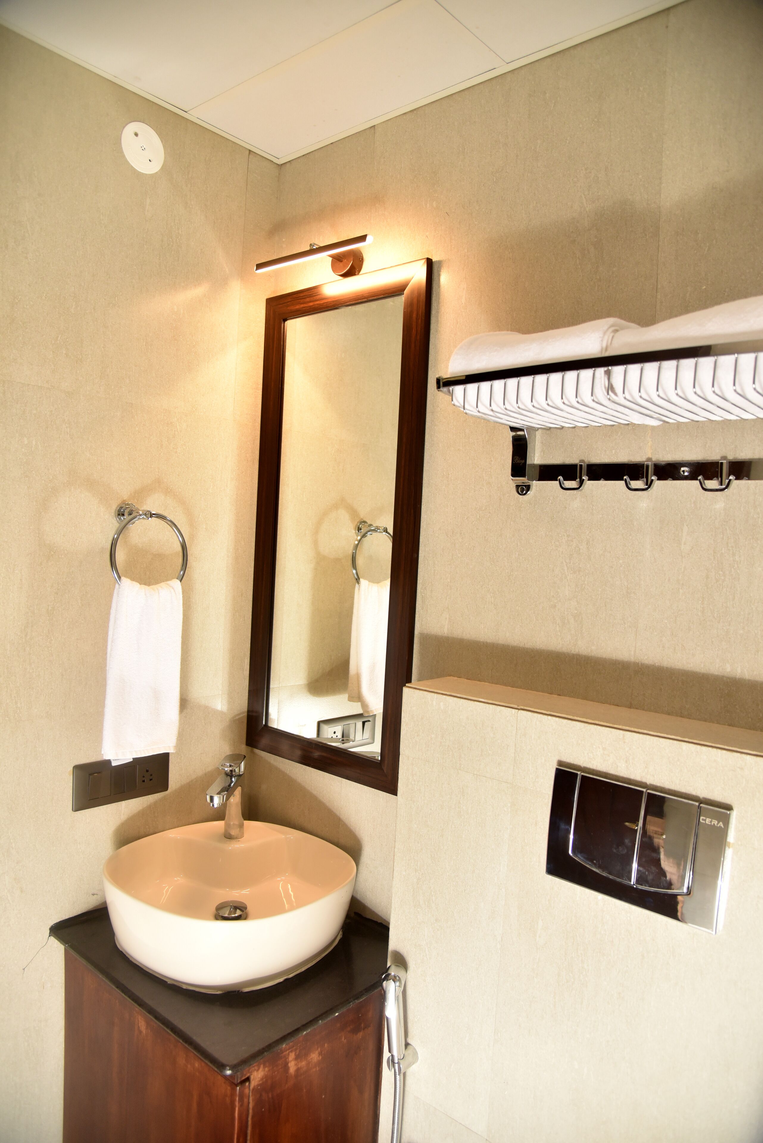 A bathroom with a sink, mirror, towel rack, and a towel hanging on the rack.