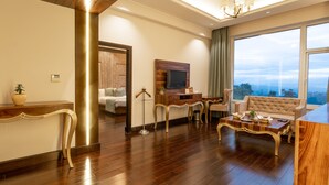 A spacious living room with a large window, a television, and a comfortable seating area. - The Orchid Shimla (Shimla)