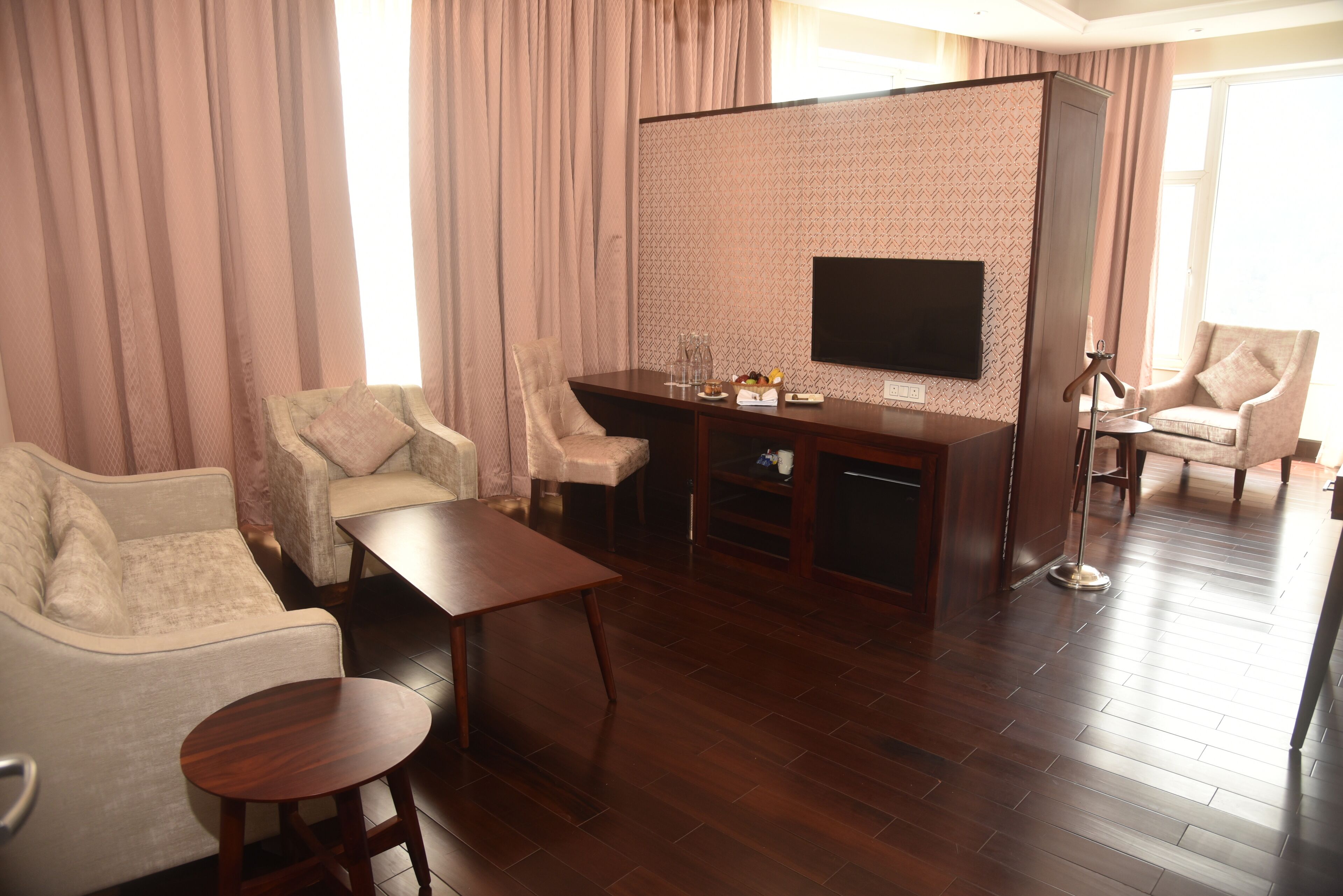 Una sala de estar moderna con un sofá, sillones, una mesa de centro, un televisor y suelo de madera.