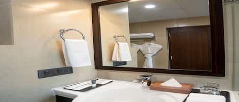 A modern bathroom with a large mirror, white sink, and towel rack.