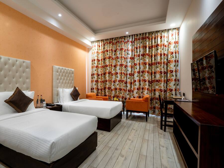 Habitación de hotel con dos camas, un televisor y un escritorio.