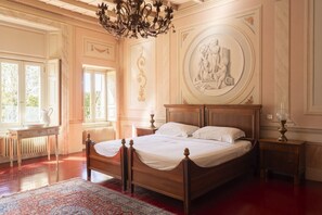 Une chambre classique avec un lit en bois, une grande fenêtre et un plafond décoratif.