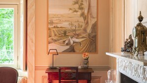 A room with a large landscape painting, a wooden desk with a lamp, and a fireplace with decorative items. - La Corte. A historic house at the gates of Bergamo. (Mozzo - (Bg))