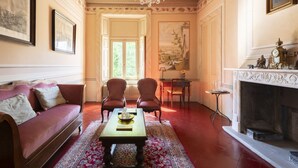 A room with a red sofa, two chairs, a table, a fireplace, and a large window. - La Corte. A historic house at the gates of Bergamo. (Mozzo - (Bg))