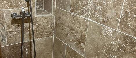 Baño con ducha, cabezal de ducha de mano y manguera de ducha.