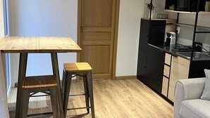 Una cocina moderna con suelo de madera, un armario blanco y negro empotrado y un sofá gris.