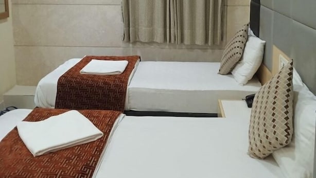 A hotel room with two beds, a picture on the wall, and an air conditioning unit. - Bentley Hotel Churchgate (Mumbai)