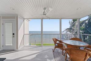 A covered balcony with a glass door leading to a view of the ocean. - Captiva Hide-A-Way 1A (Captiva)