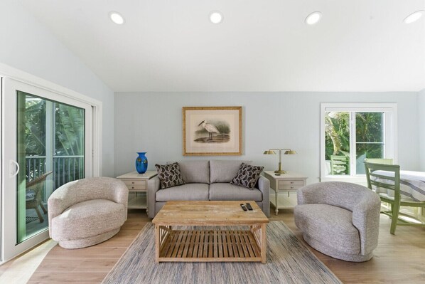 A spacious living room with a grey sofa, two armchairs, a wooden coffee table, and a framed picture on the wall. - Captiva Hide-A-Way 1A (Captiva)