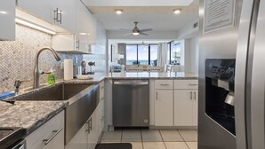 A modern kitchen with a granite countertop, stainless steel appliances, and a view of the ocean through large windows. - Spectacular Atlantic Views from this Oceanfront Unit with 3 Balconies! (North Myrtle Beach)