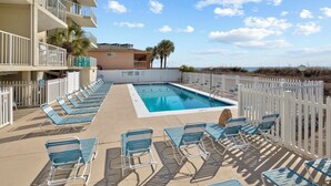 A pool area with lounge chairs and a building with balconies. - Spectacular Atlantic Views from this Oceanfront Unit with 3 Balconies! (North Myrtle Beach)