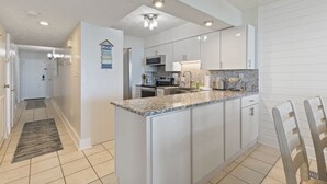 A modern kitchen with white cabinets, granite countertops, and a herringbone backsplash. - Spectacular Atlantic Views from this Oceanfront Unit with 3 Balconies! (North Myrtle Beach)