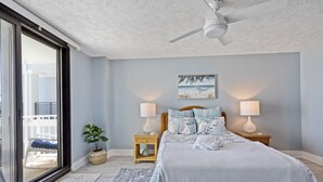 A bedroom with a bed, two bedside tables with lamps, a ceiling fan, a large window, and a view of the outside balcony. - Spectacular Atlantic Views from this Oceanfront Unit with 3 Balconies! (North Myrtle Beach)