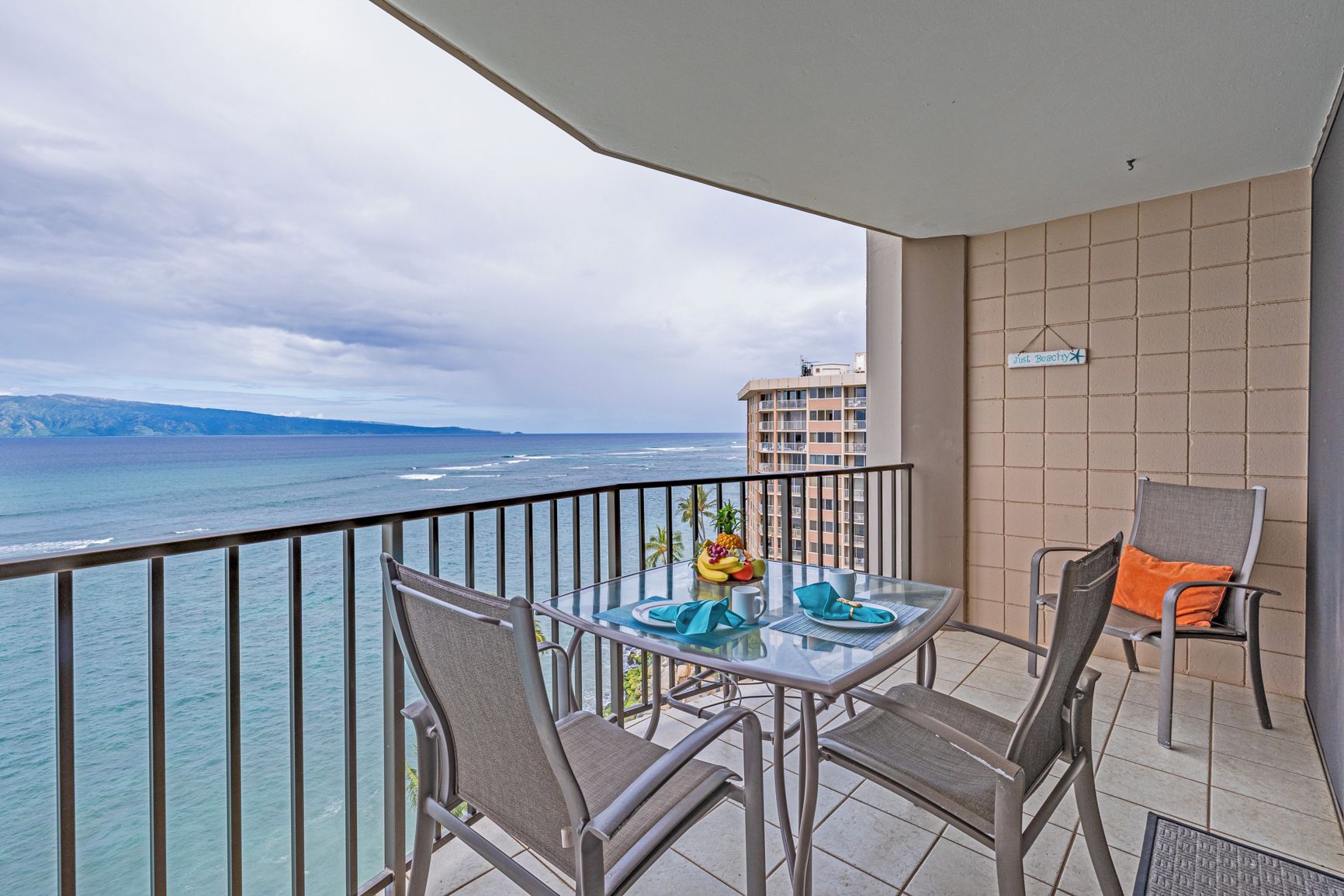 A balcony with a glass table, two chairs, and a small fruit bowl.