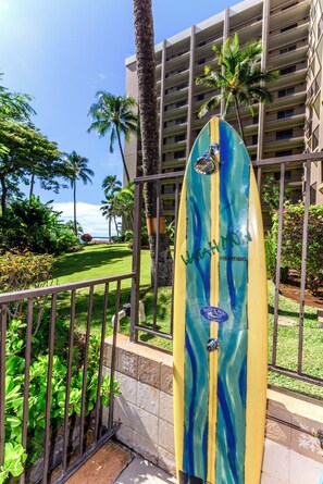 A surfboard with "Valley Isle Resort" text, surrounded by a lush garden and palm trees, with a hotel building in the background.