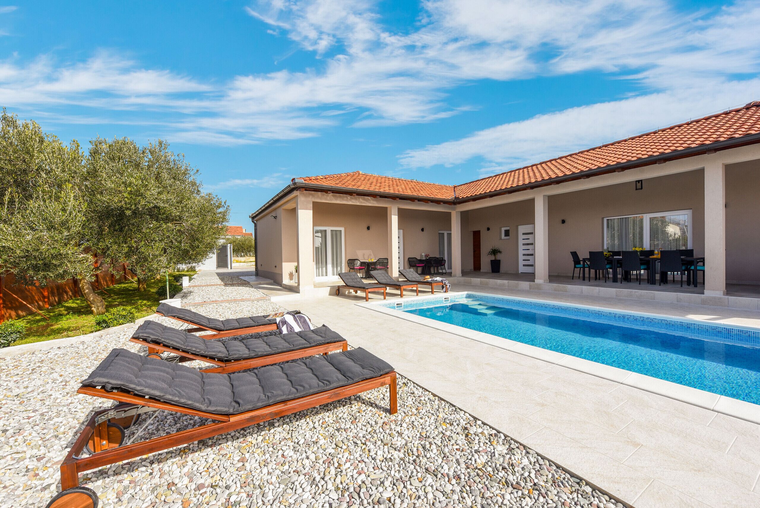 A swimming pool area with lounge chairs and a covered patio.