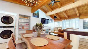 Een gezellig chaletinterieur met een houten eettafel, een open haard en een aan de muur bevestigde televisie.